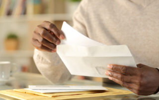 Black man hands putting a letter inside an envelope