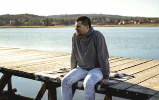 Young man sitting on wooden pier