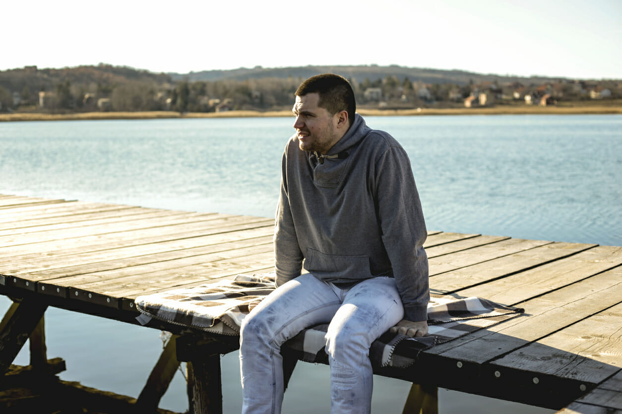 Young man sitting on wooden pier