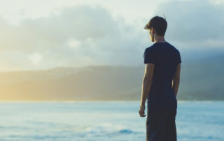 Young man on top ocean cliff during sunset