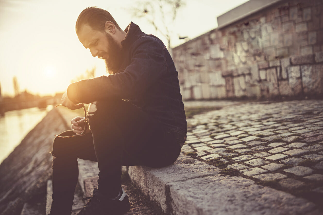 Sober man sitting by the river and enjoying life