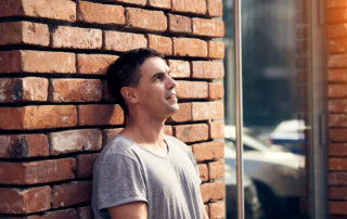 Portrait of man standing near brick wall.