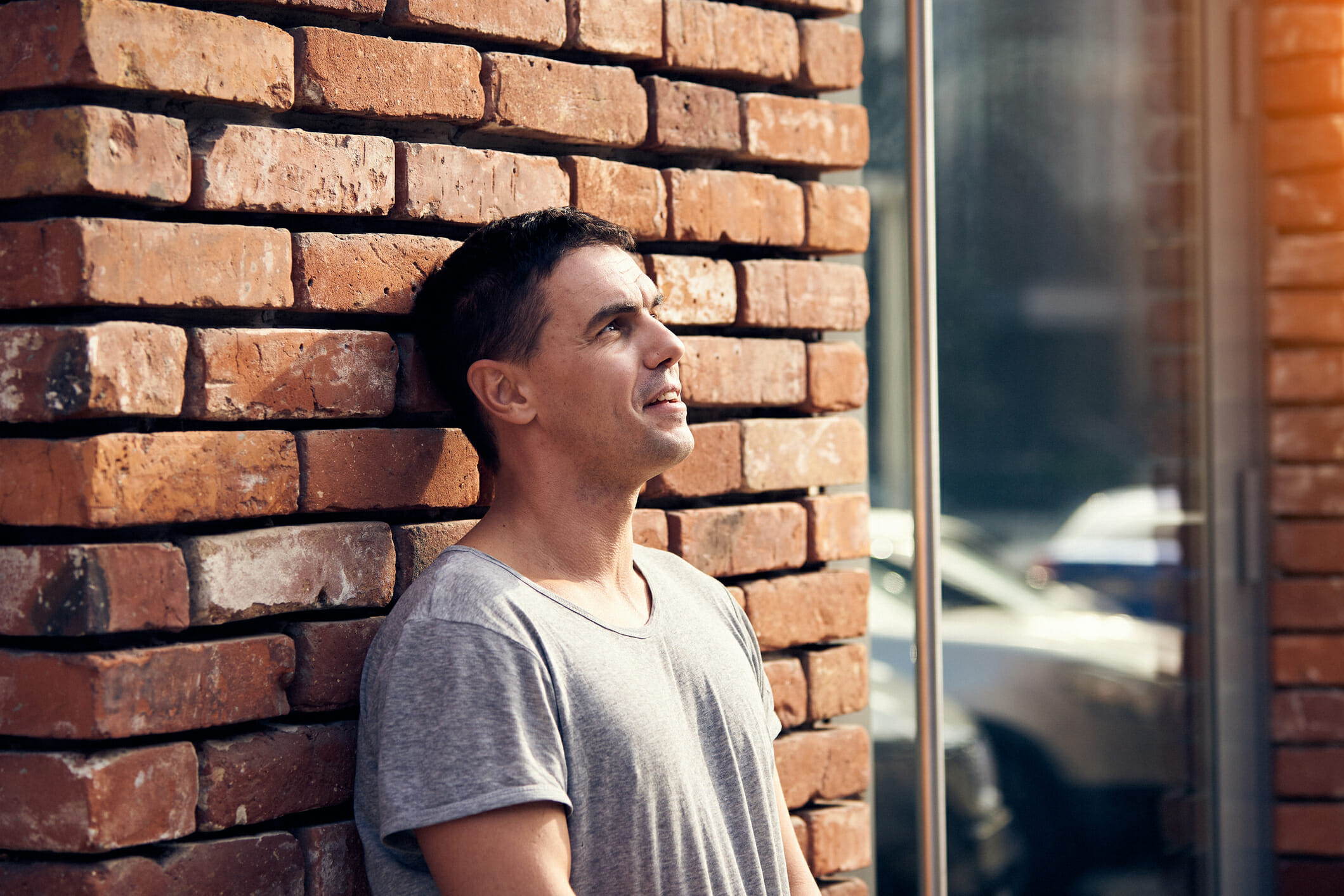 Portrait of man standing near brick wall.