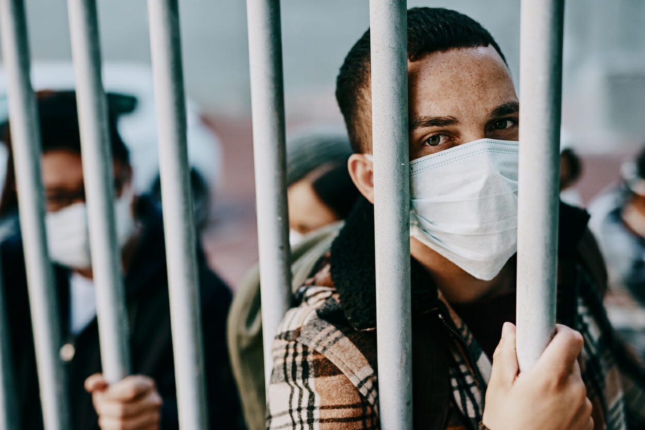 Shot of a young man wearing a mask in a jail