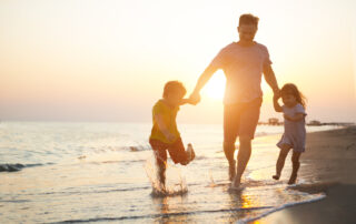 Happy father and two children playing on the beach.