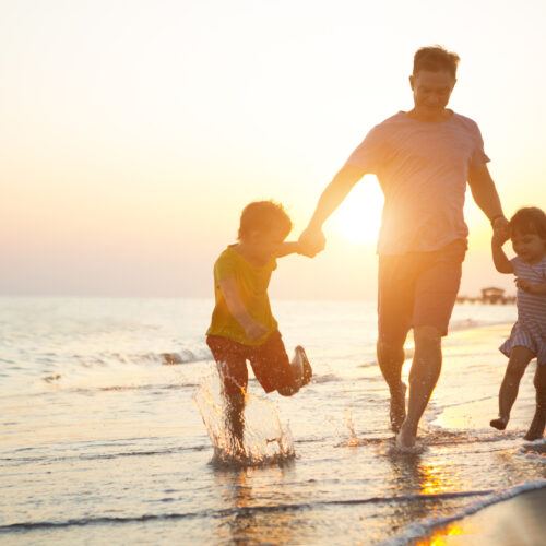 Happy father and two children playing on the beach.