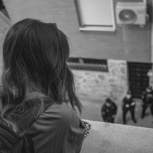 Young woman looking at policemen from the balcony