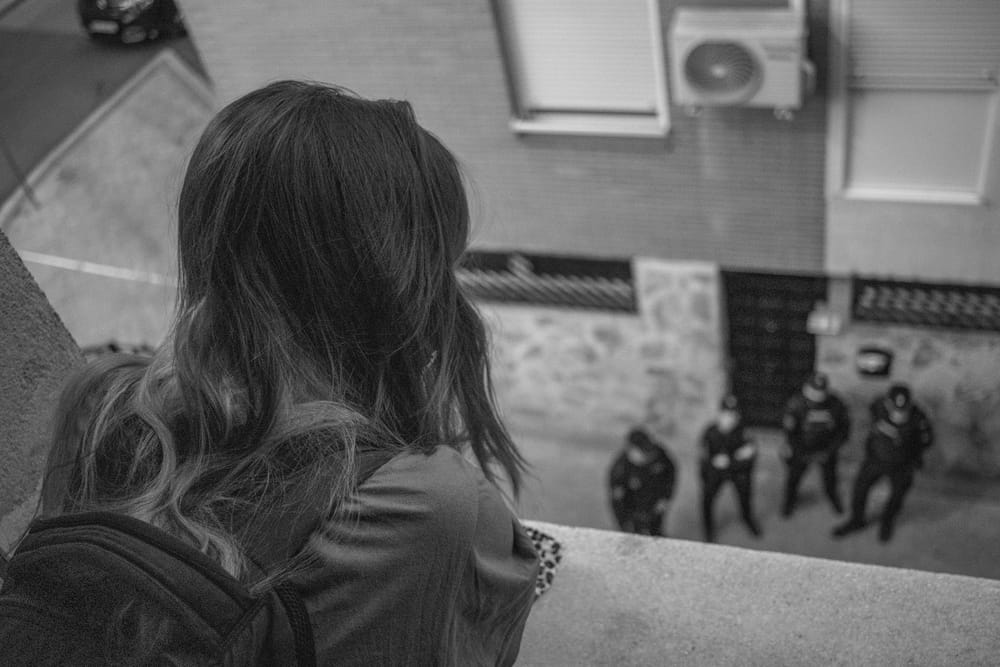 Young woman looking at policemen from the balcony