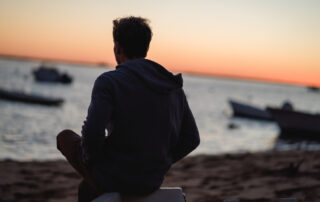 Young man sits on a beach.