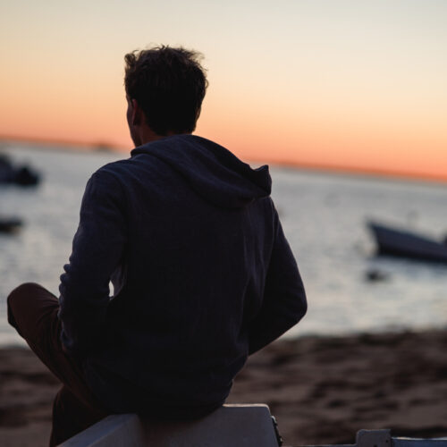 Young man sits on a beach.